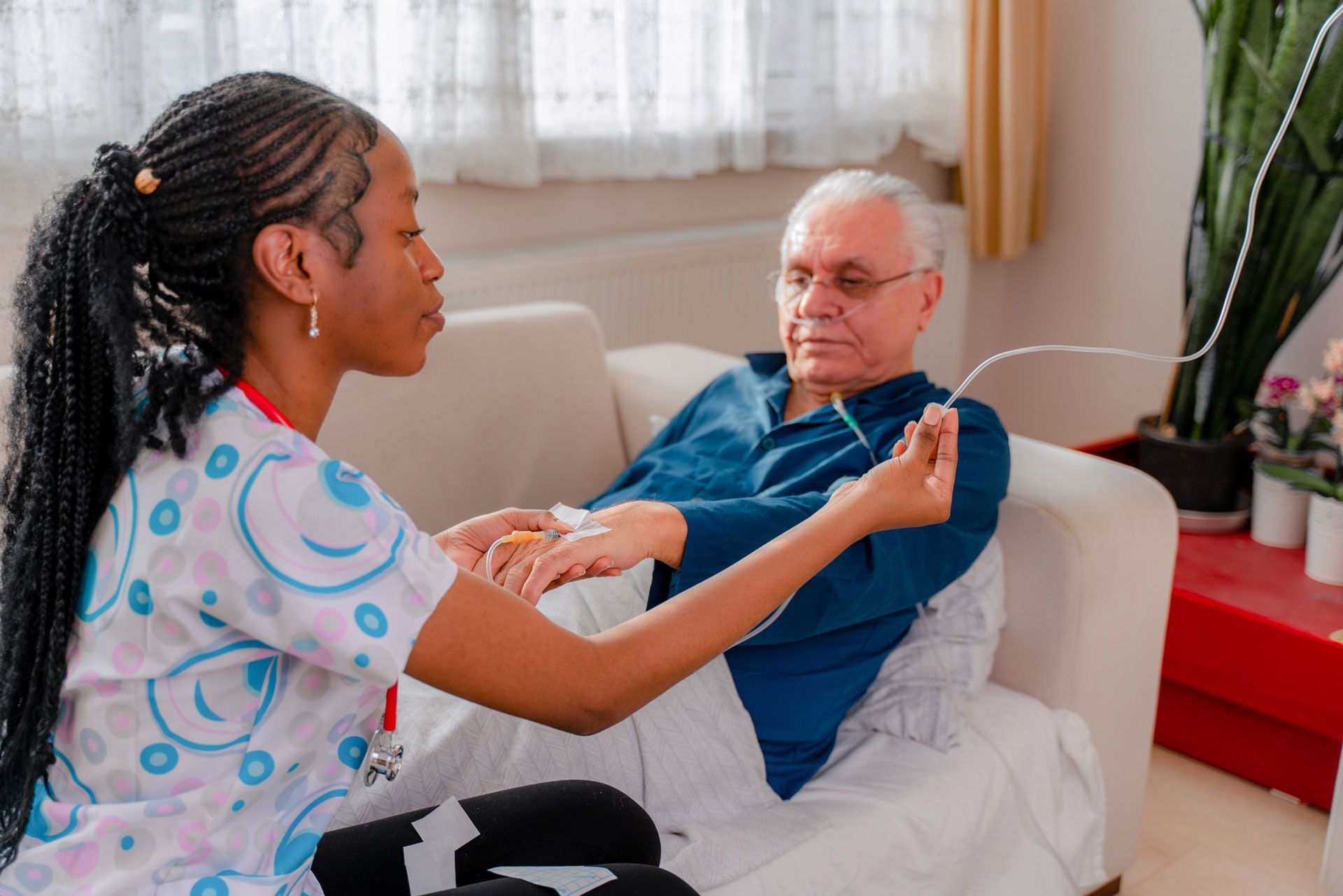 A nurse is holding the hand of an elderly man on a couch.