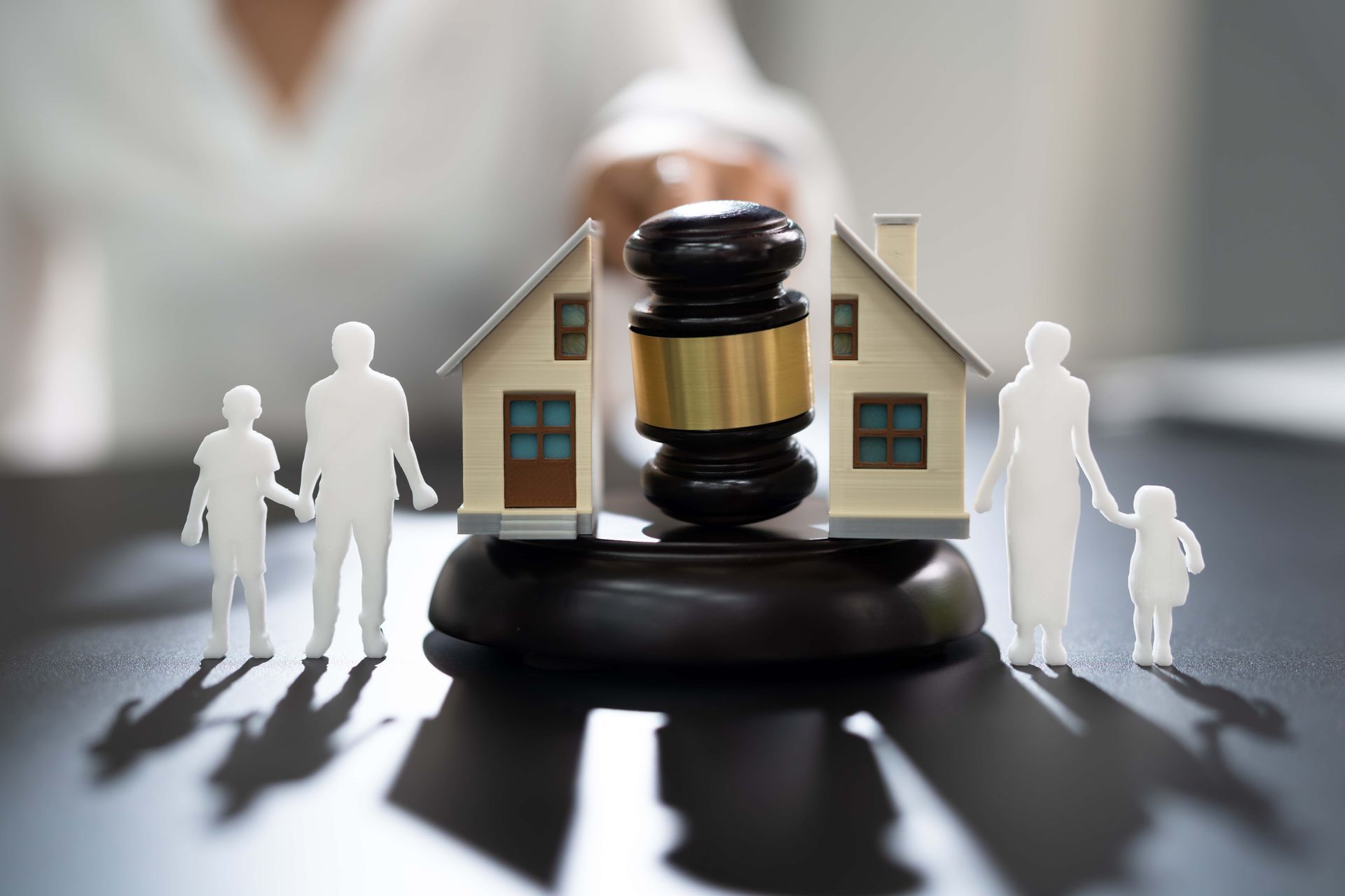 Gavel in front of a house model with family figures, suggesting a legal or property dispute