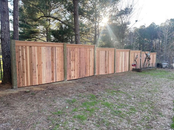 A wooden fence is surrounded by trees in a yard.