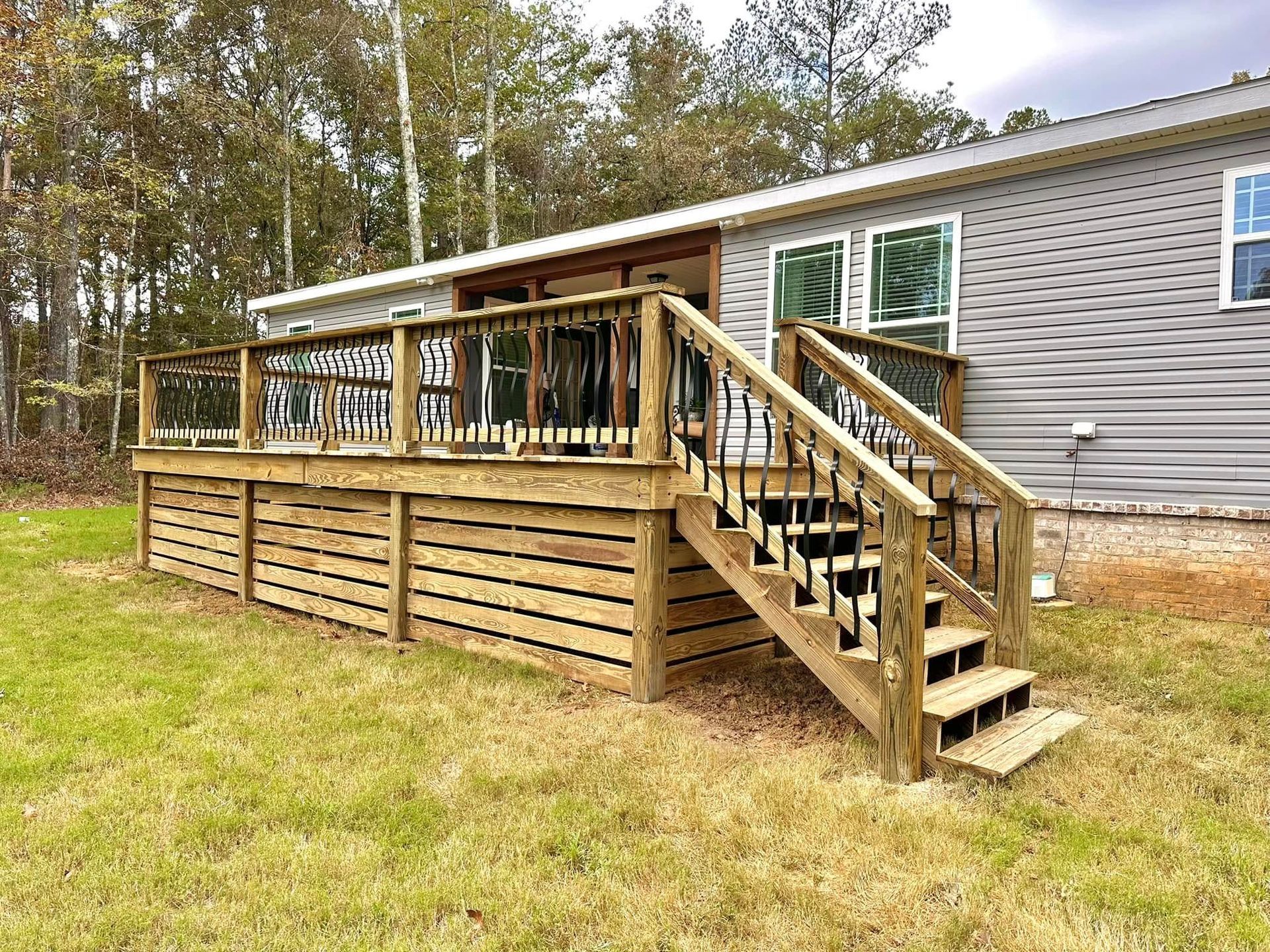 A mobile home with a wooden deck and stairs in front of it.