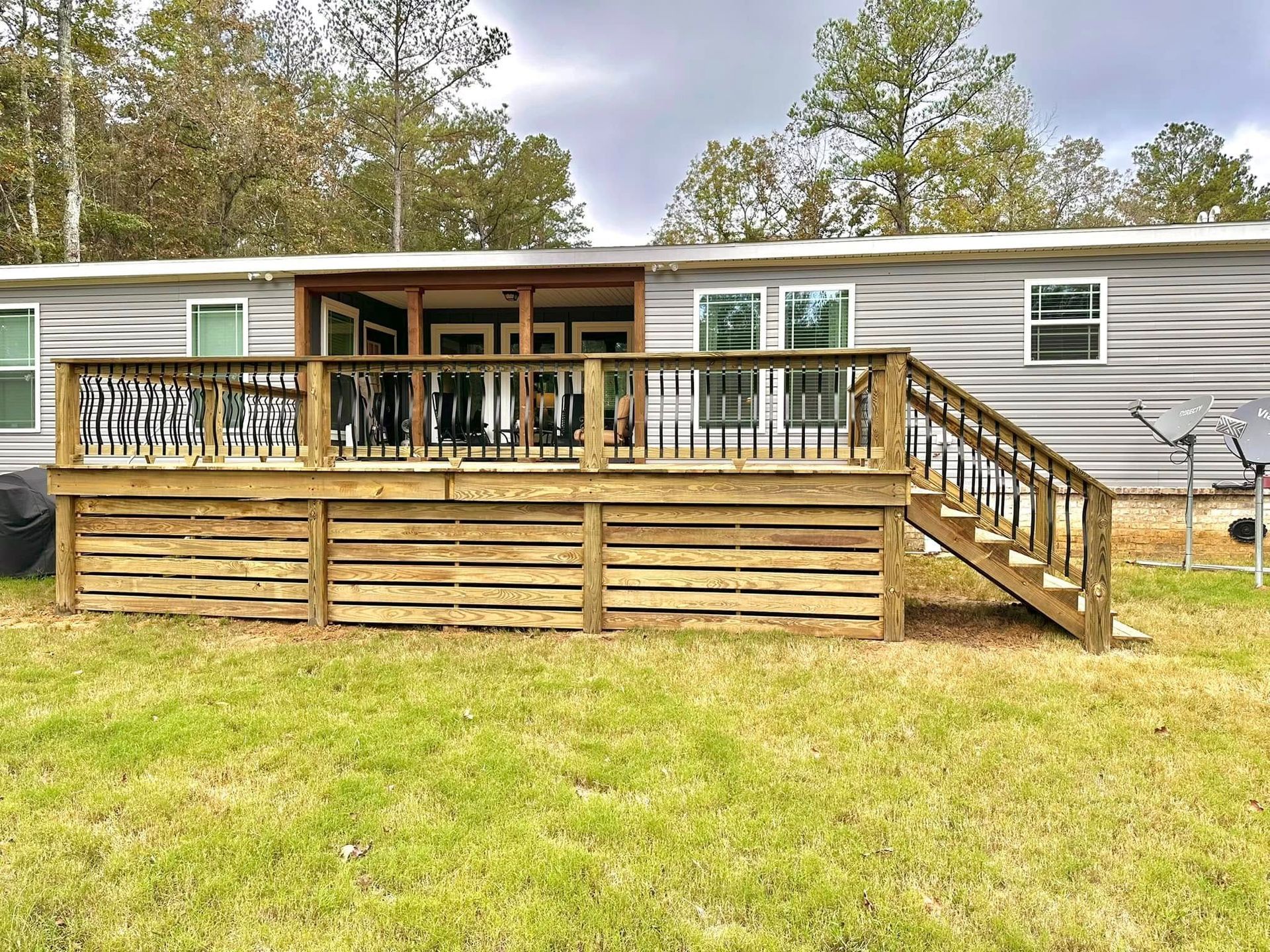 A mobile home with a large wooden deck and stairs.