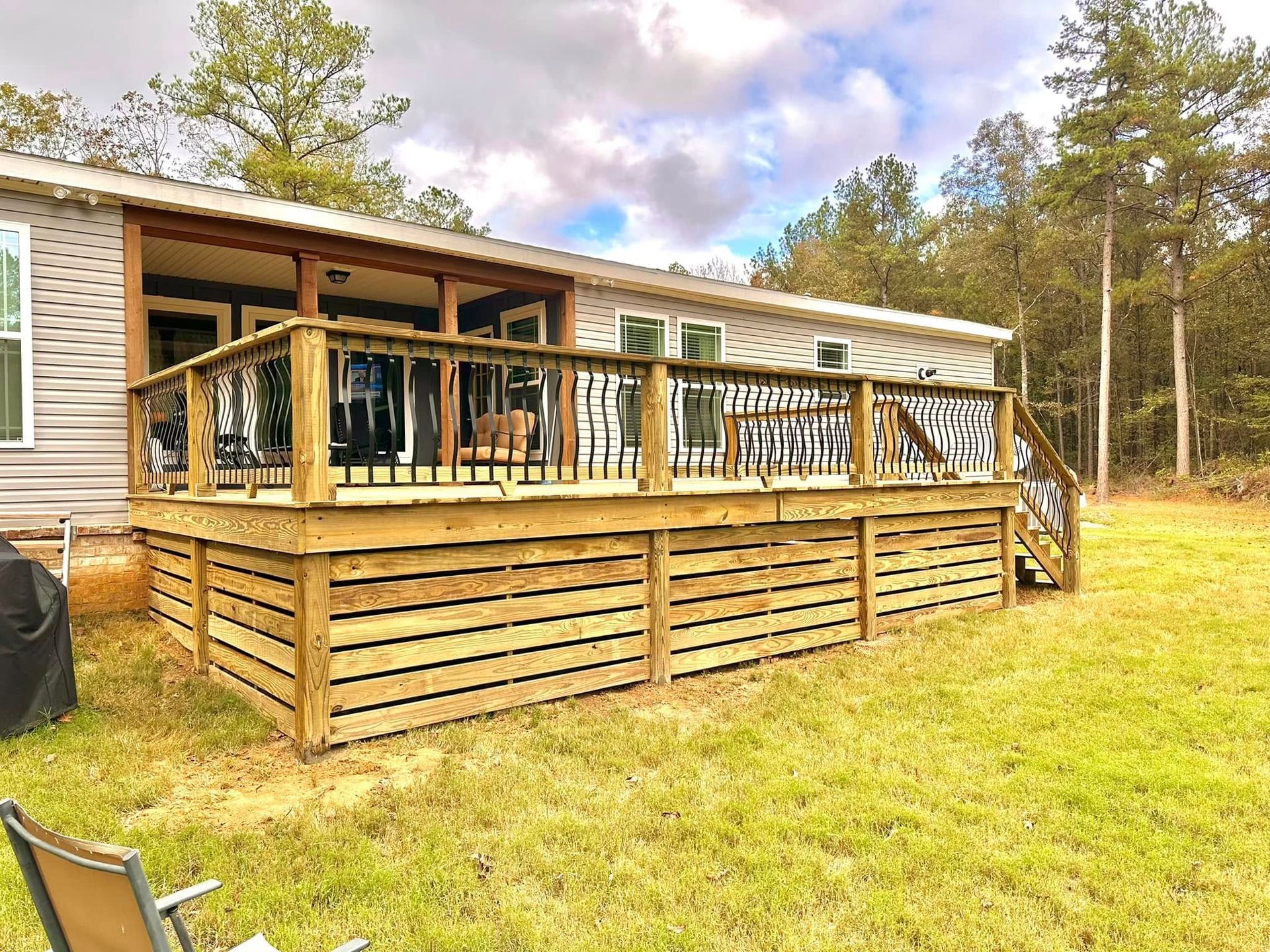 A mobile home with a large wooden deck in front of it.