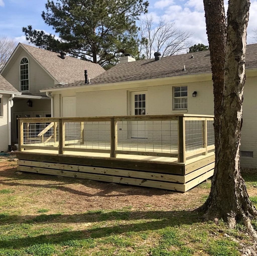 A white house with a wooden deck in front of it.