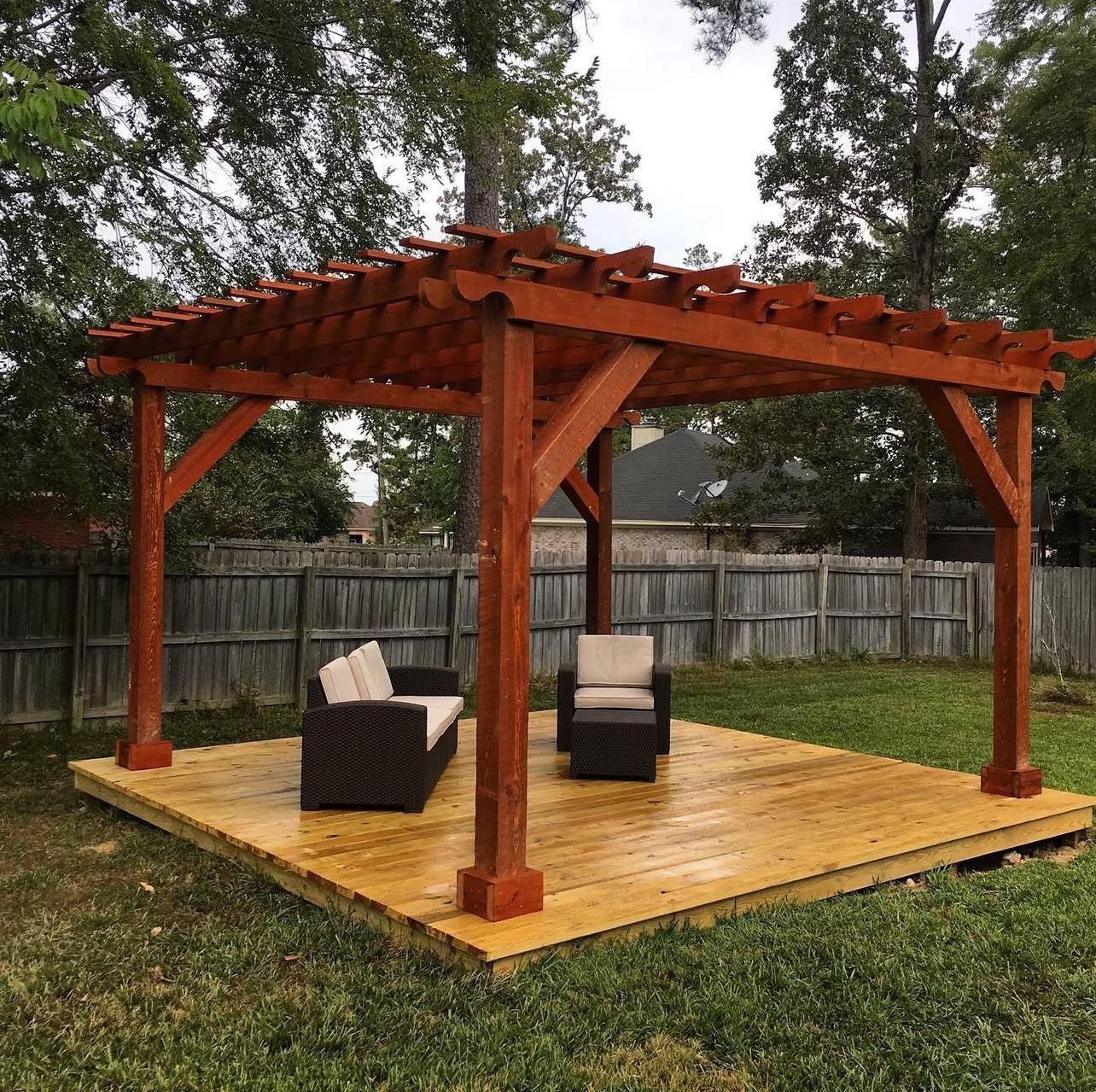 A wooden pergola with a couch and chairs underneath it