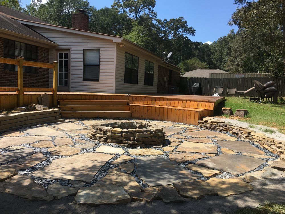 A fire pit in the middle of a patio in front of a house.