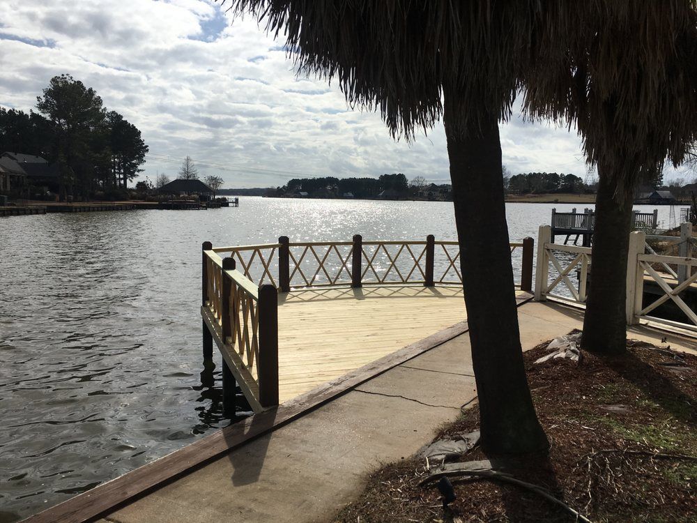 A wooden dock overlooking a body of water with palm trees in the foreground.