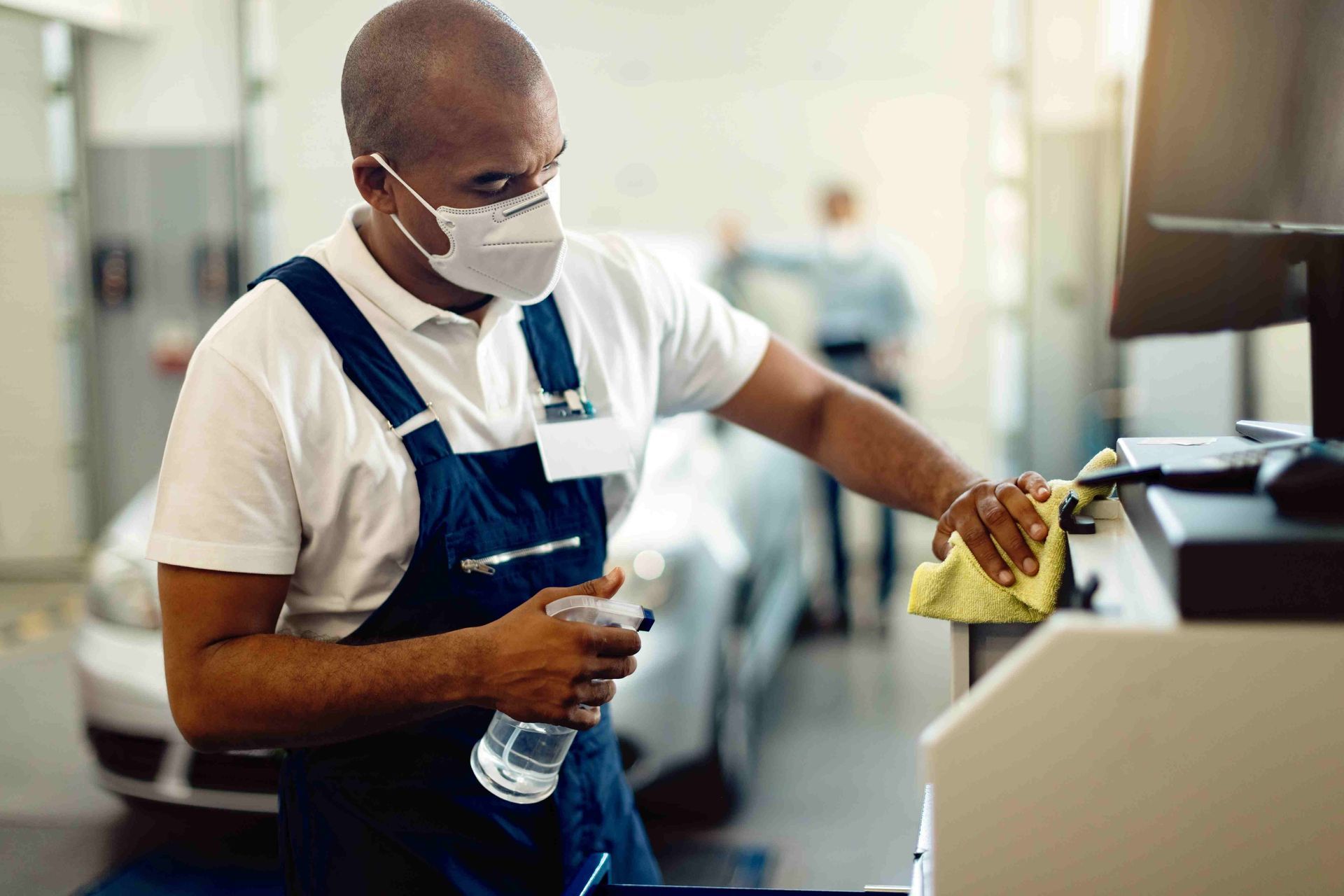 a man wearing a mask is cleaning a machine in a garage