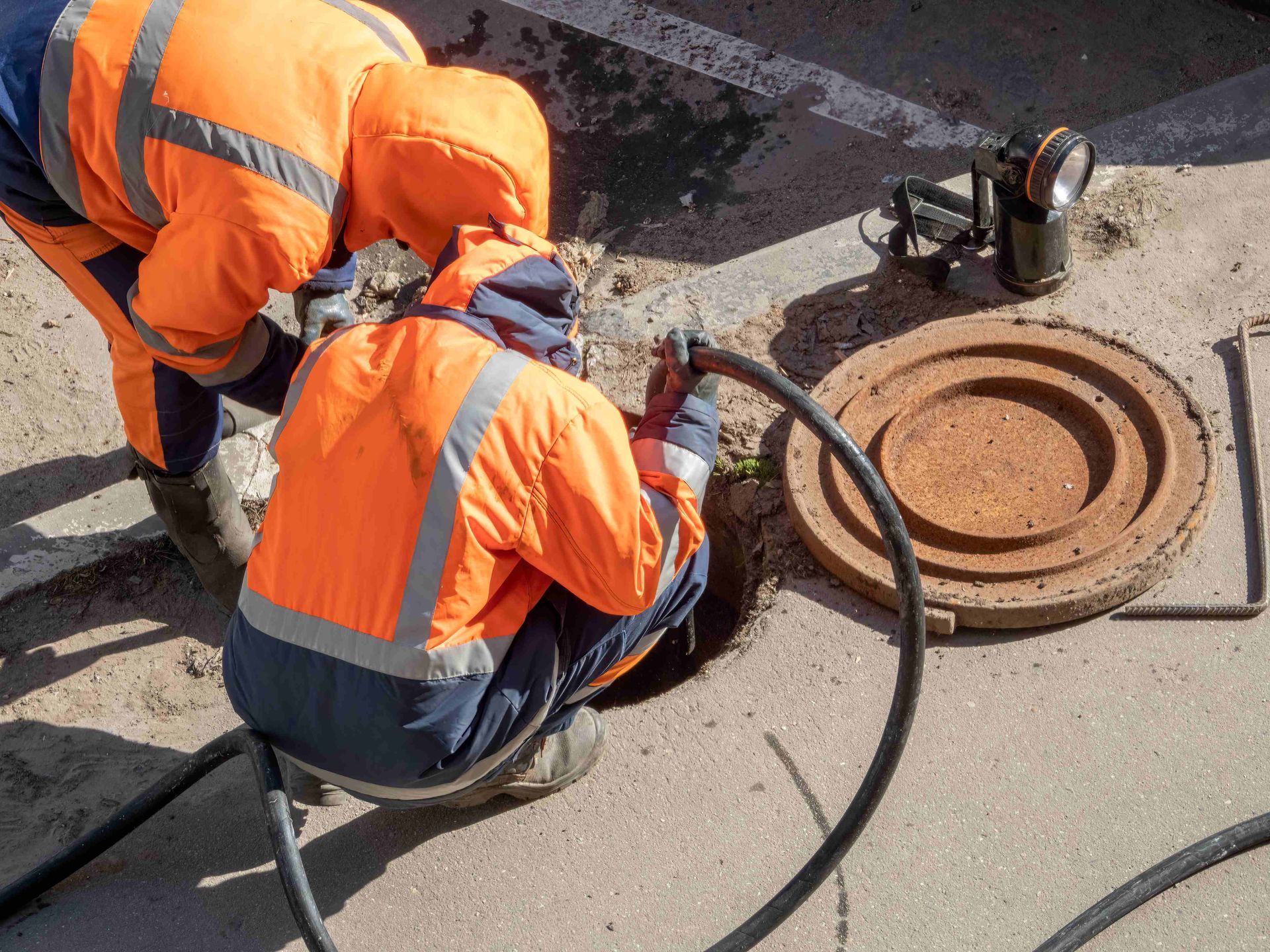 two men are working on a manhole cover