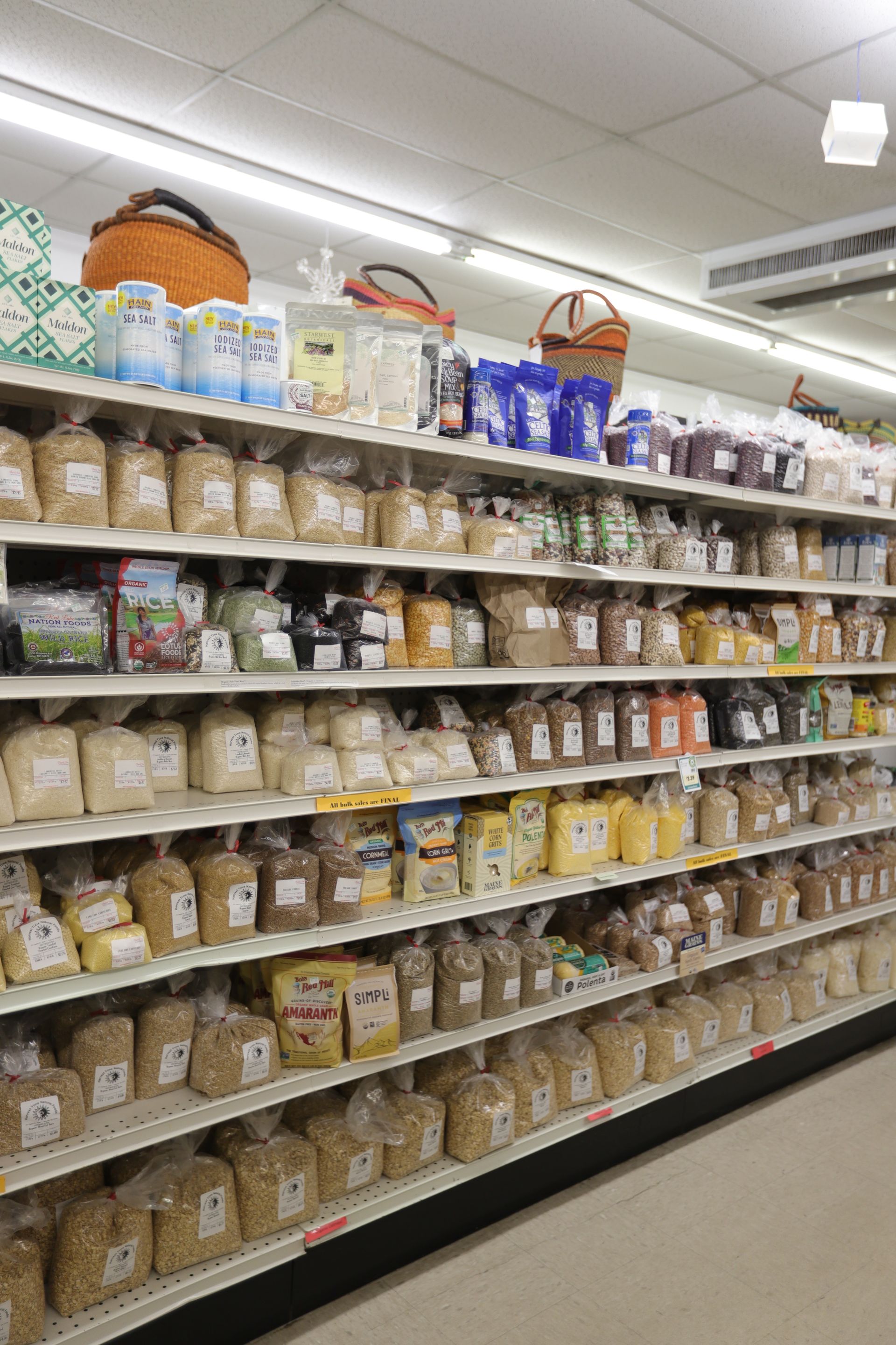 Store shelves stocked with a wide variety of packaged grains, beans, and dry goods in a well-lit grocery aisle.