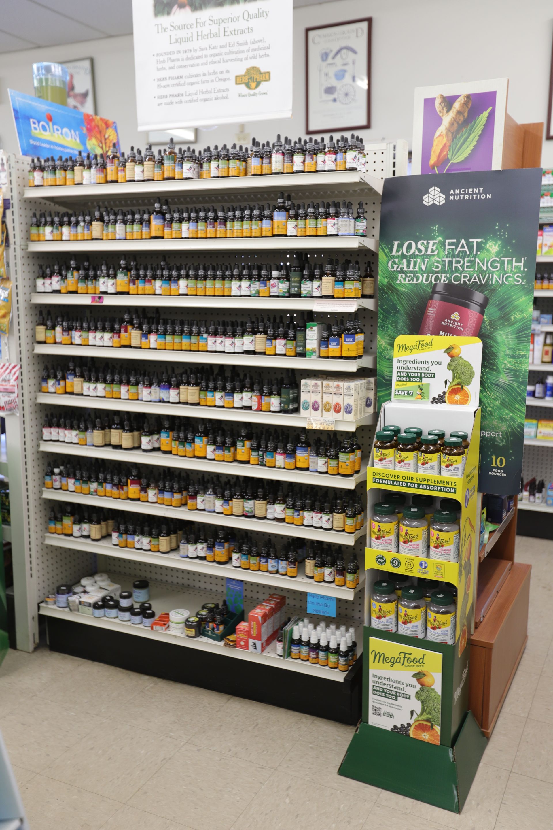 A store aisle display featuring shelves filled with numerous small amber bottles and a branded stand for supplements.