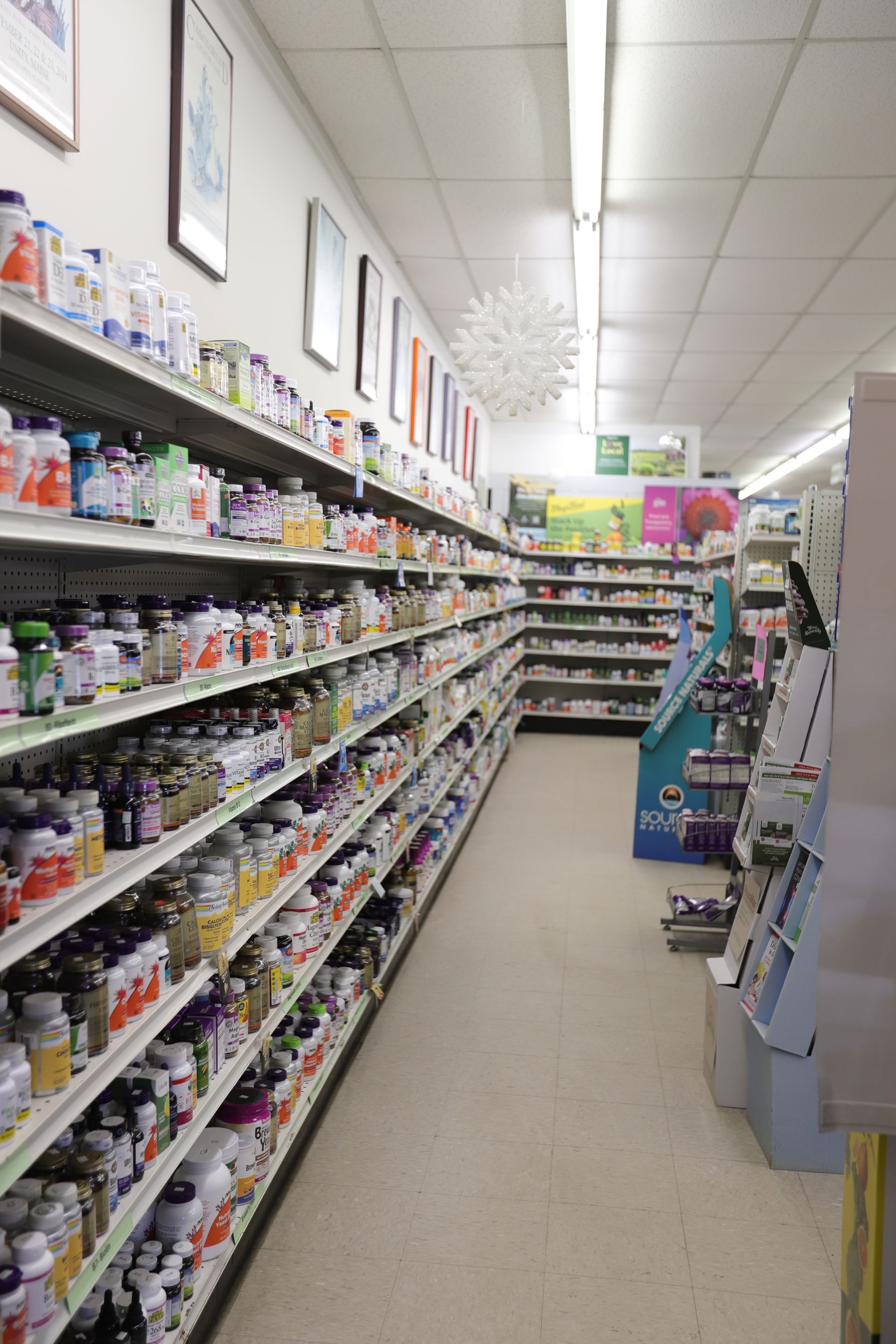 A store aisle filled with numerous shelves of health supplements and bottles, stretching into the background.