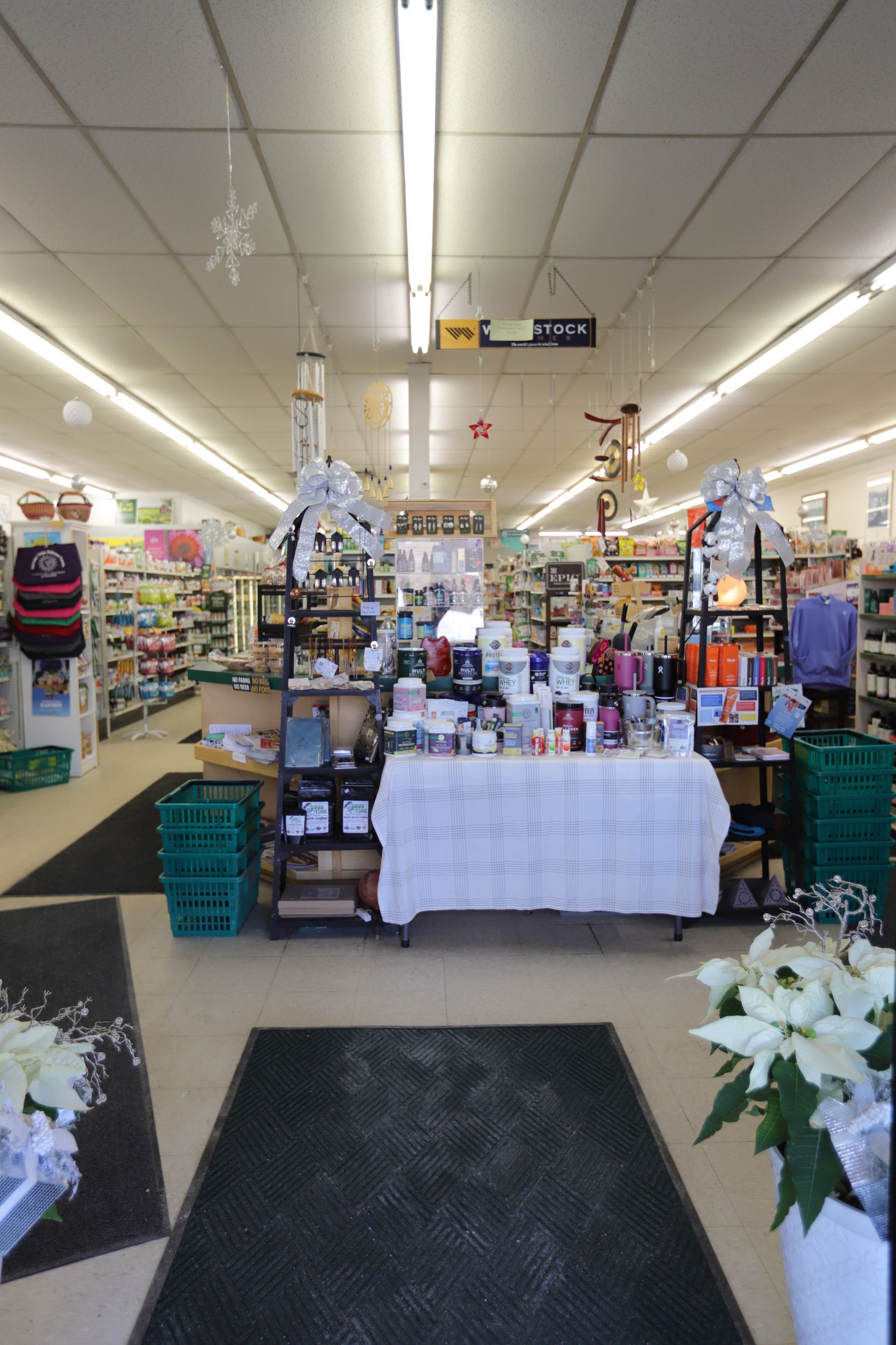 A view into a retail store entrance with a central display table, shelves, baskets, and festive holiday decor.