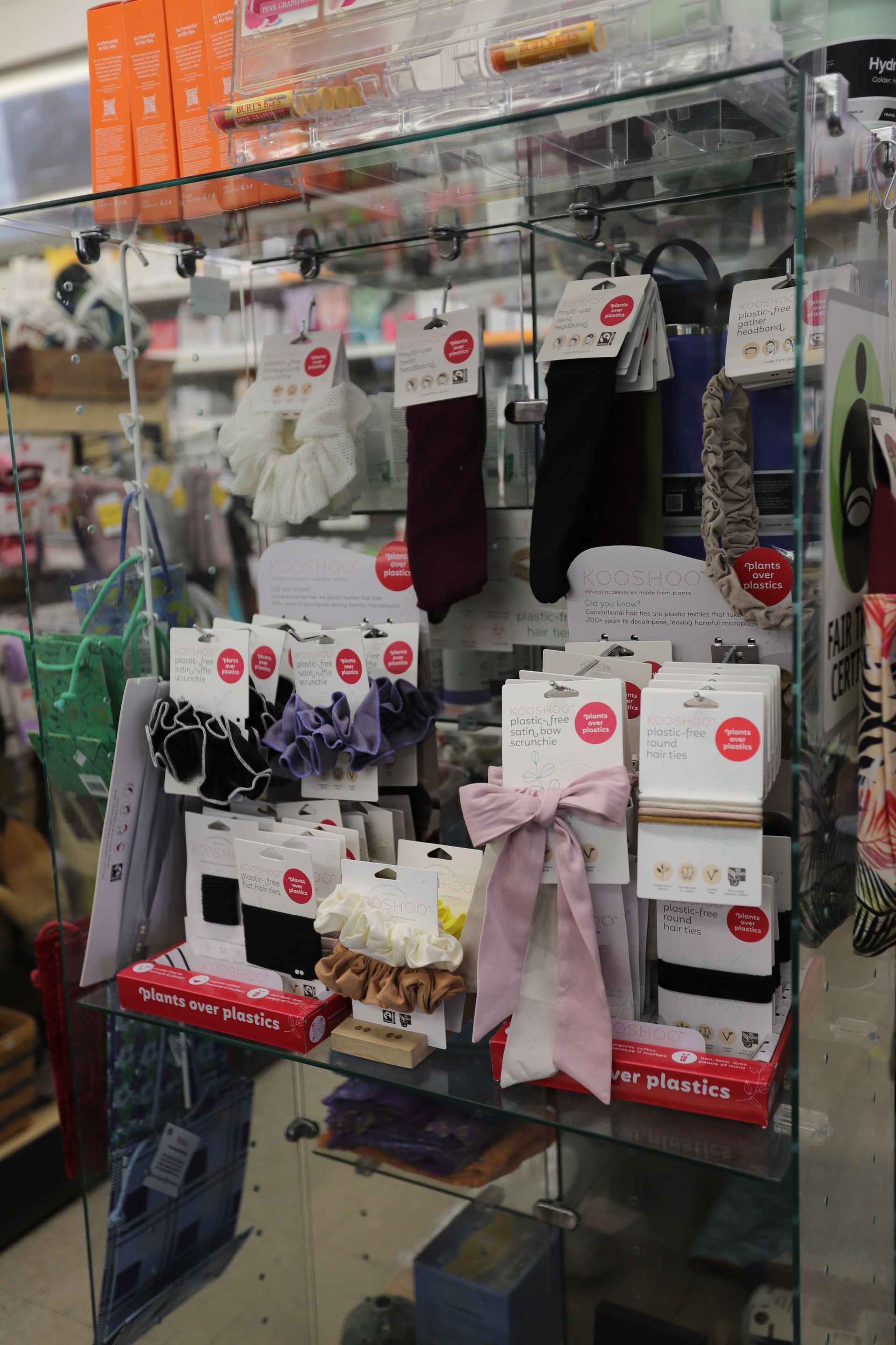 A display case in a retail store filled with assorted hair accessories like scrunchies, headbands, and hair bows.