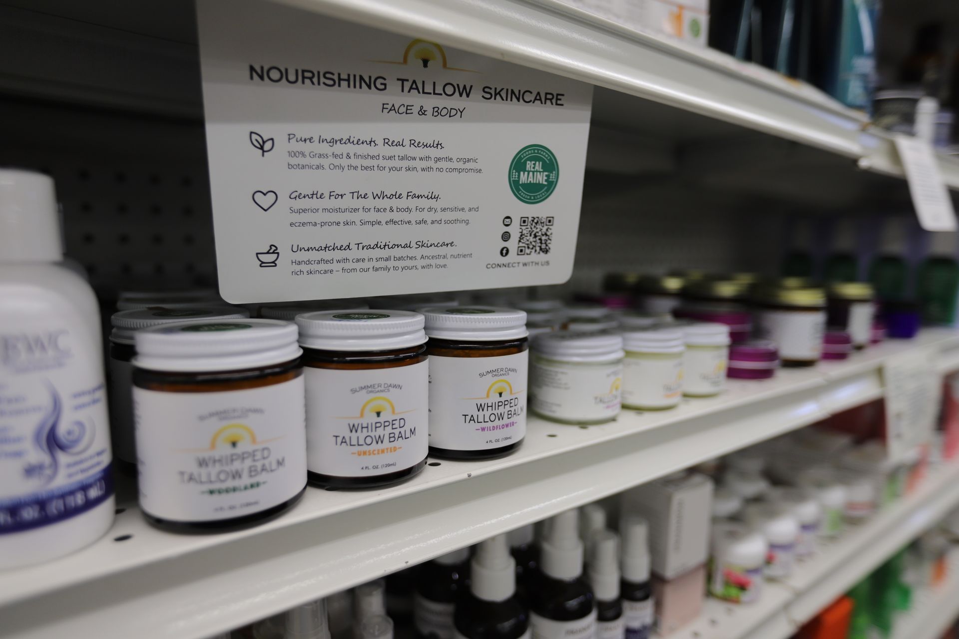 A store shelf features small jars of whipped tallow balm with a sign explaining the benefits of the nourishing skincare.