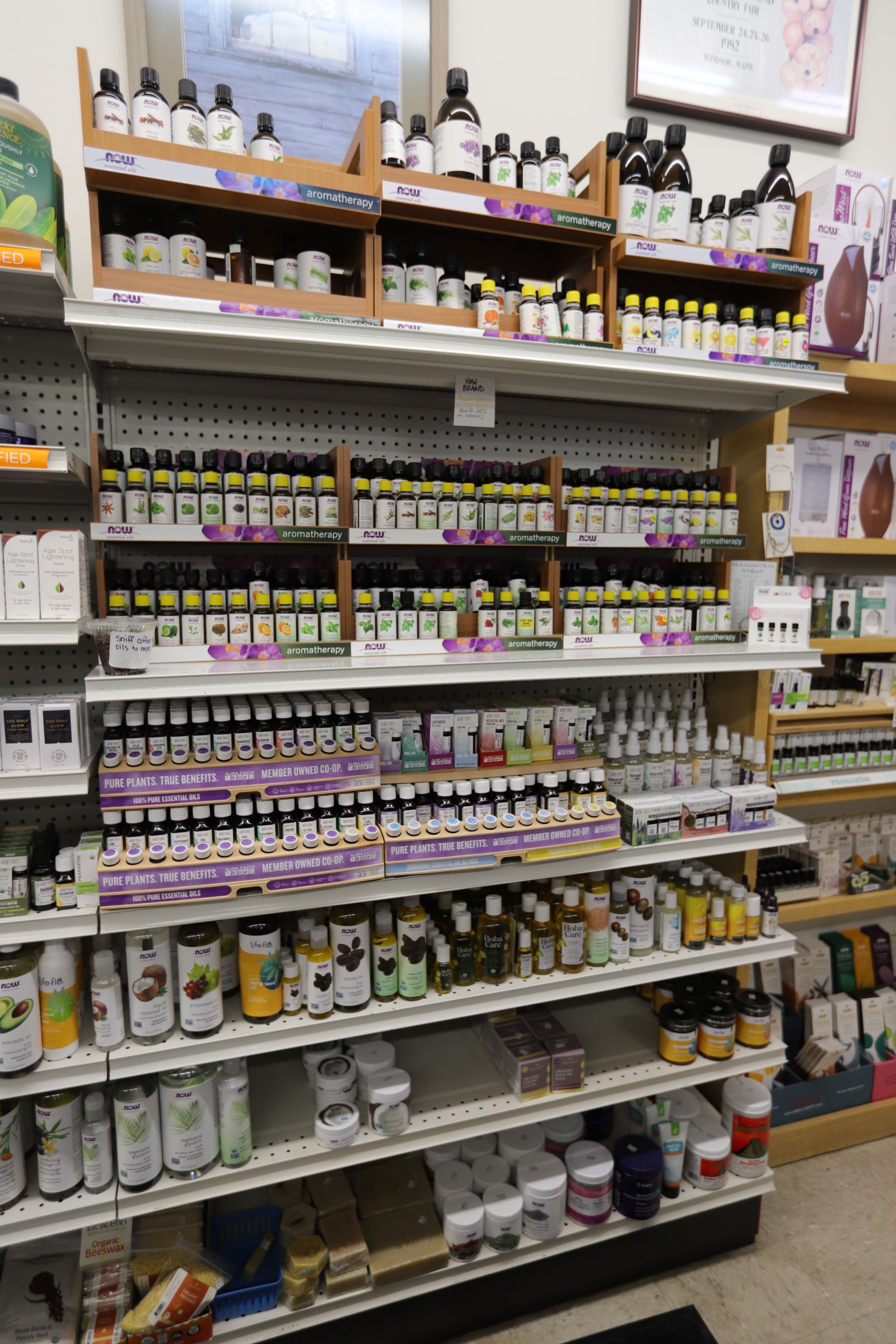 Shelves in a store are stocked with many small bottles of essential oils, organized by brand and type.