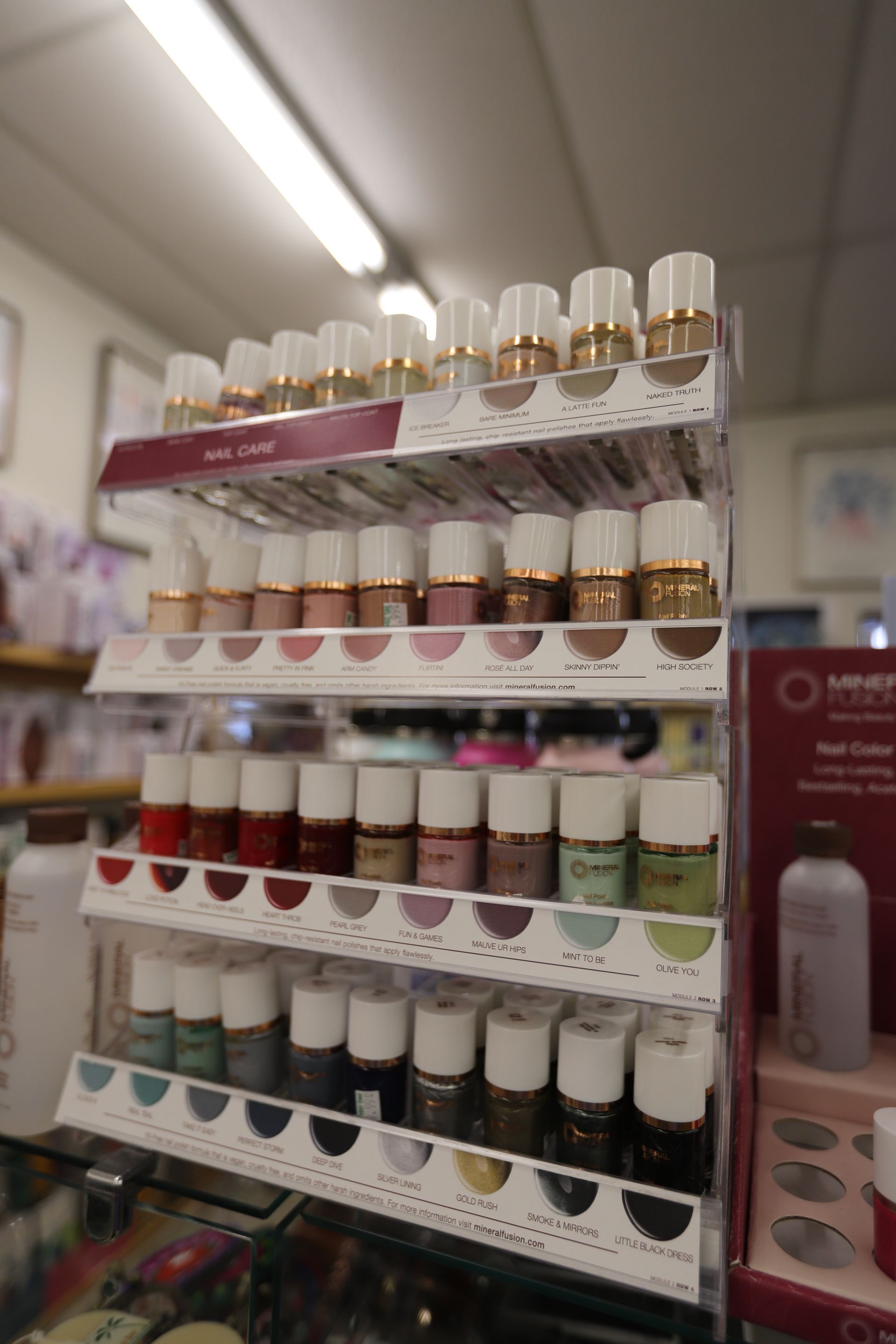 A display rack in a store featuring multiple rows of assorted nail polish bottles in various colors and shades.