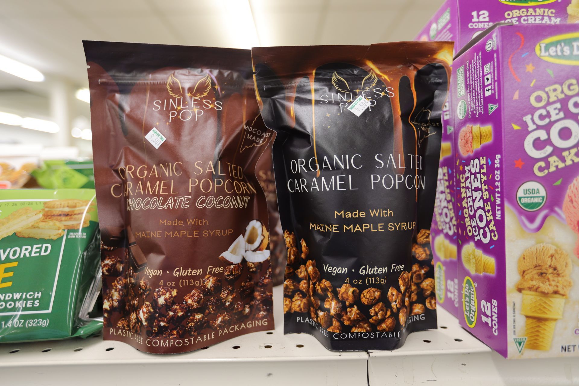 Two bags of organic popcorn and a box of organic ice cream cones on a store shelf.