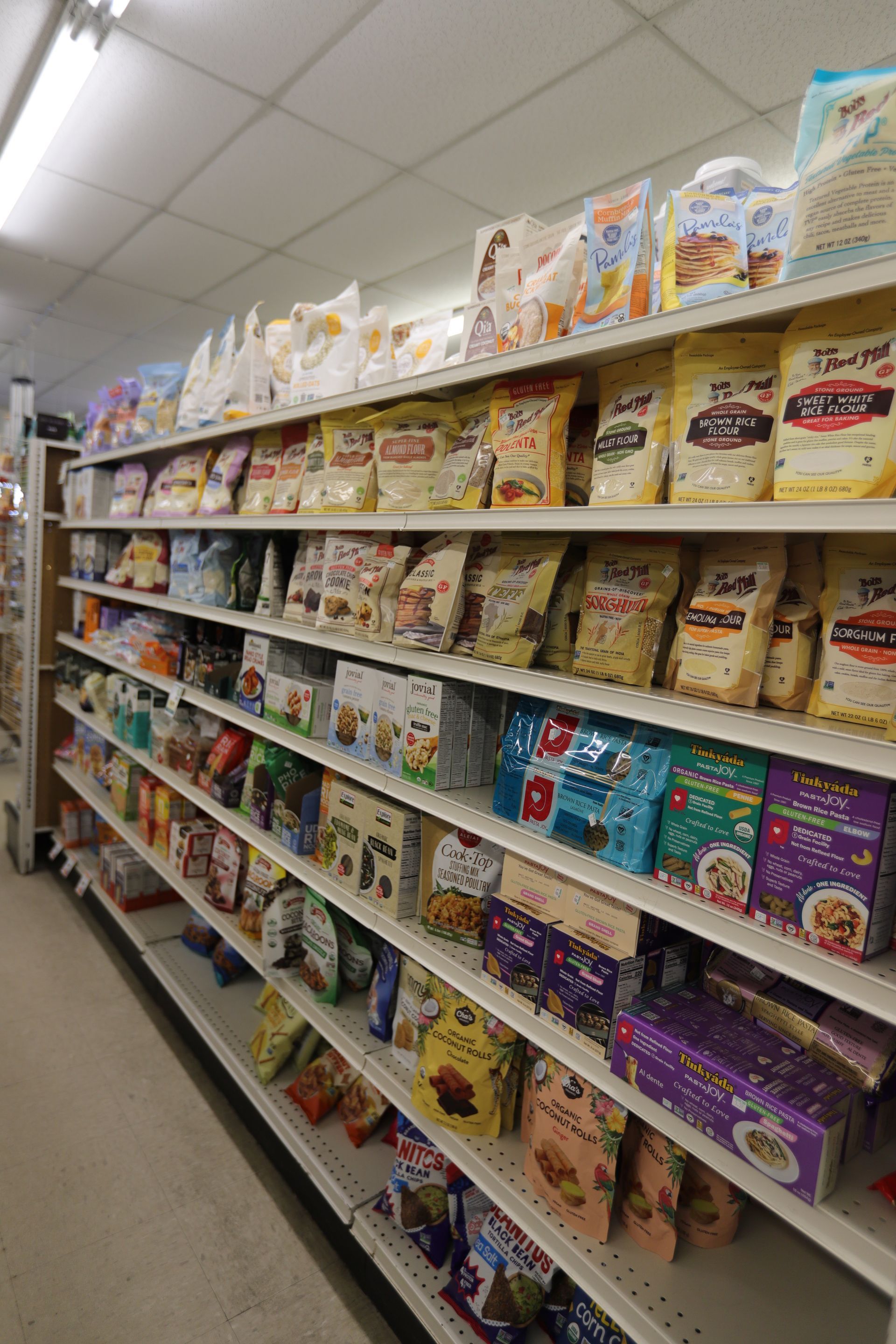 A perspective view of a supermarket aisle shelf stocked with various packaged dry food items.