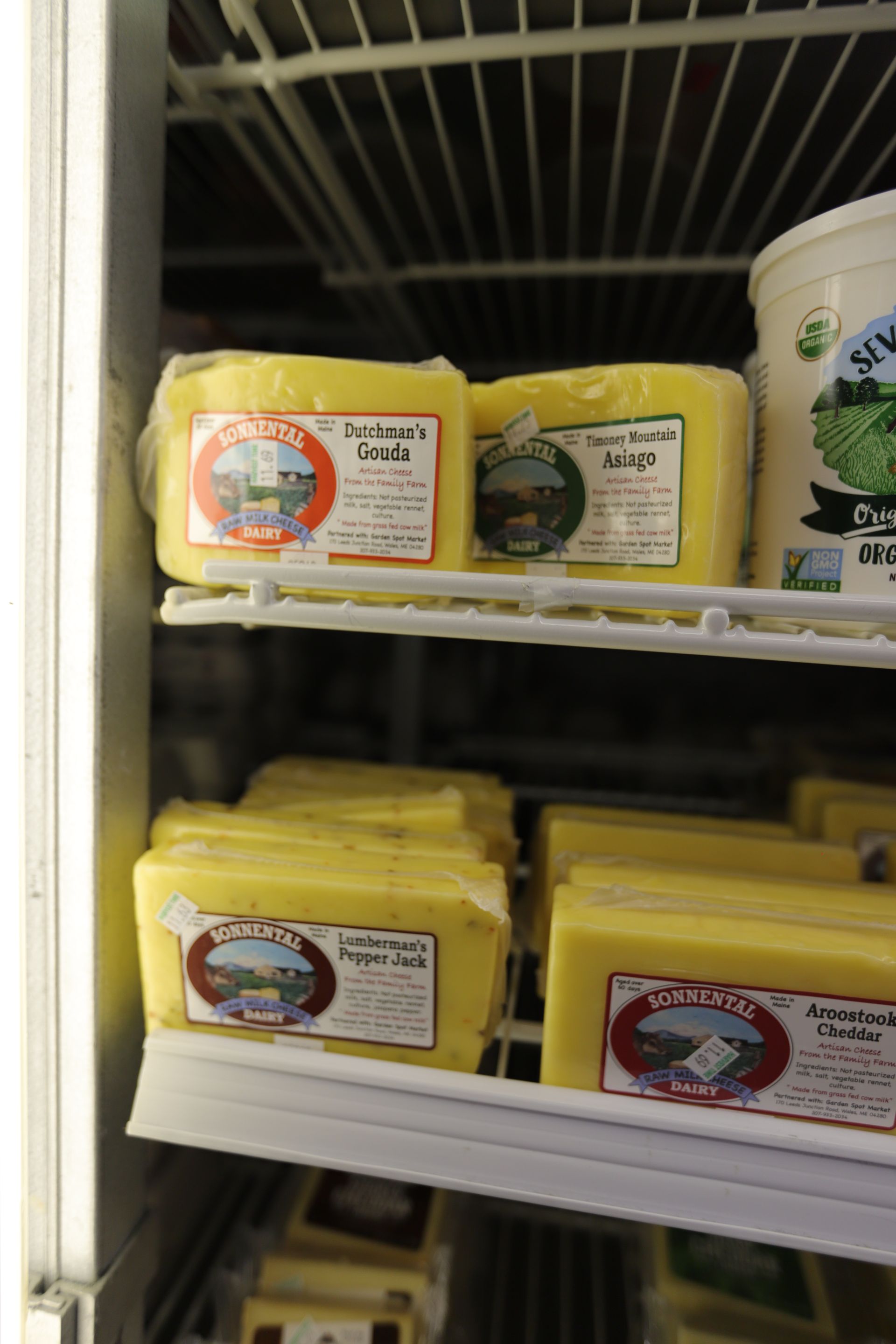 Refrigerated shelves stocked with various blocks of yellow cheese, featuring labels from Sylvan Star Cheese.