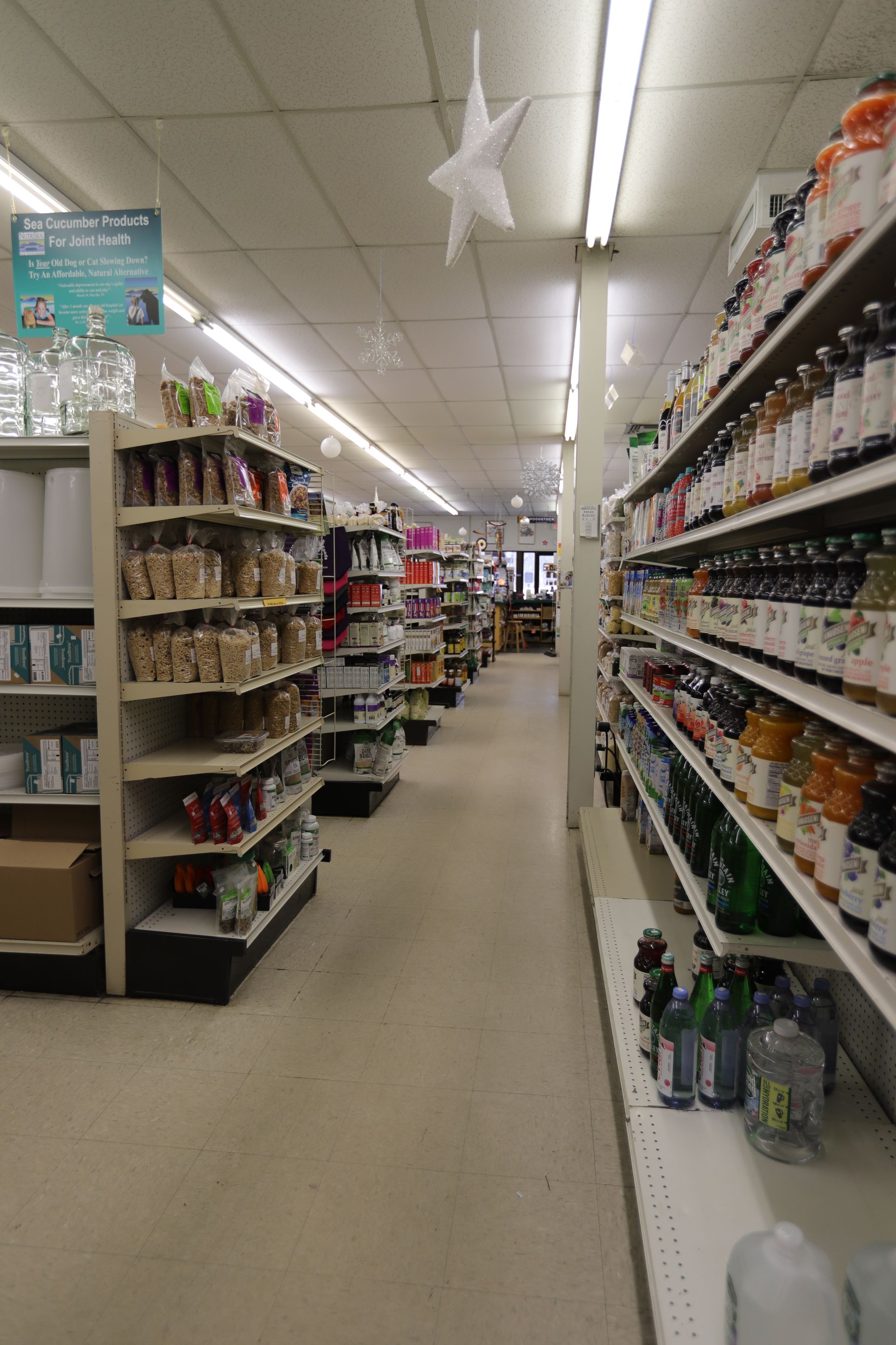 A perspective view of an aisle in a grocery store, lined with shelves filled with packaged food products and beverages.