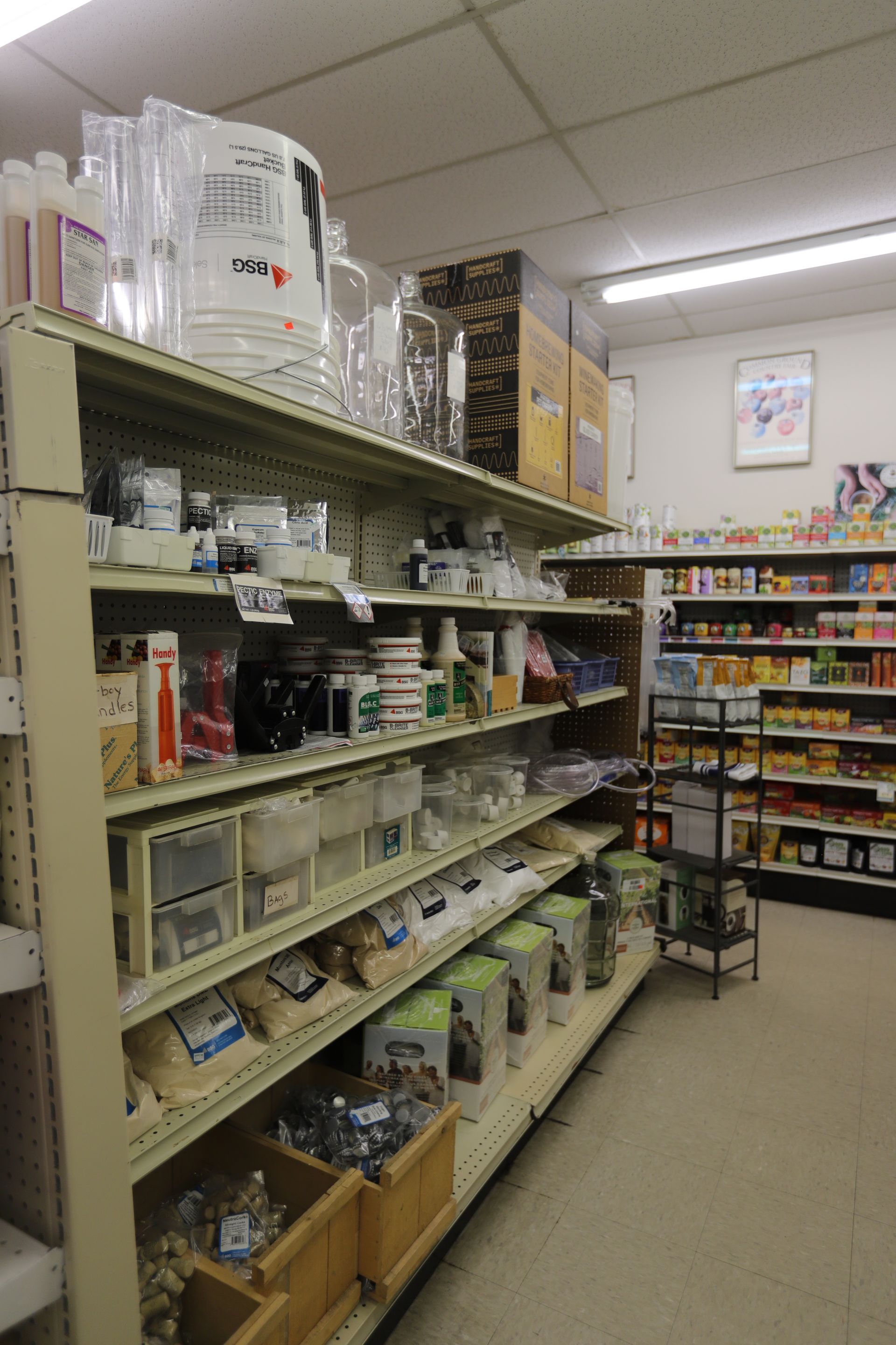 A retail aisle with shelves packed with various packaged goods, items, and small bins in a brightly lit store.