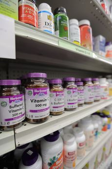 Store shelves stocked with rows of various vitamin and supplement bottles with purple and white labels.