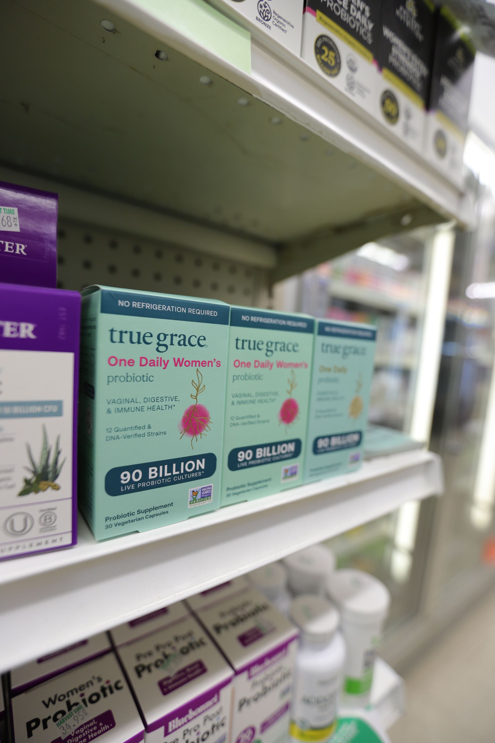 Light blue boxes of True Grace One Daily Women's Probiotics displayed on a retail store shelf.