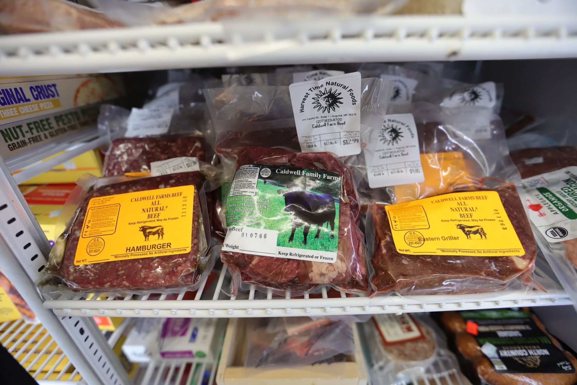 Vacuum-sealed packages of raw meat on a white wire refrigerator shelf.