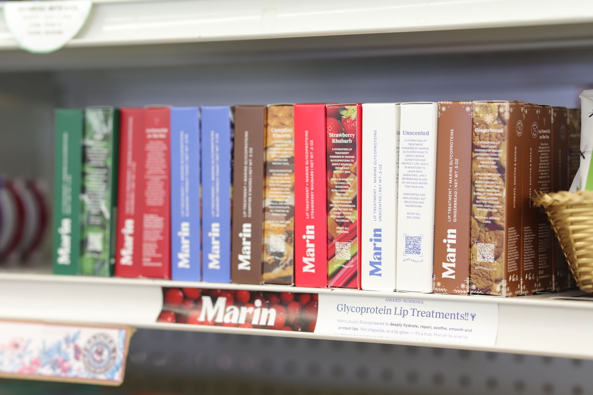A retail shelf displaying a row of colorful Marin-branded product boxes with a sign below the shelf.