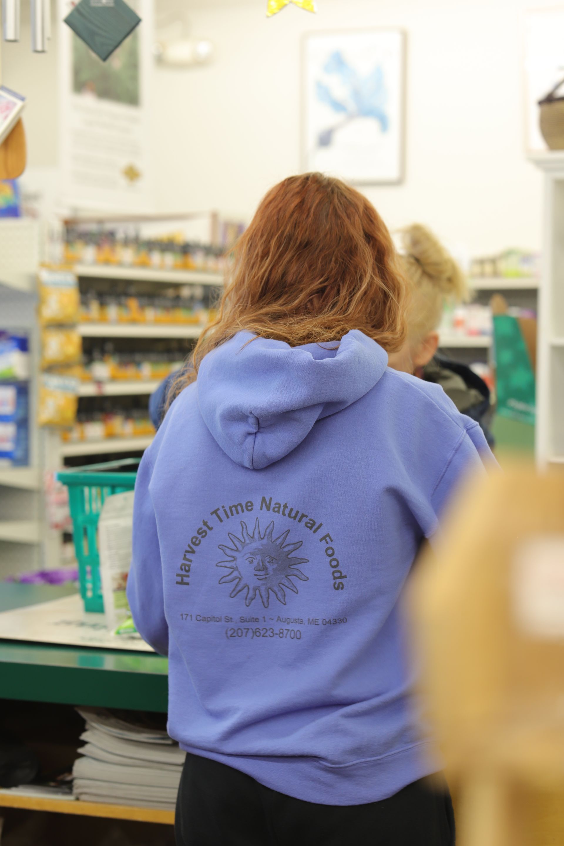 A person wears a lavender hooded sweatshirt with 