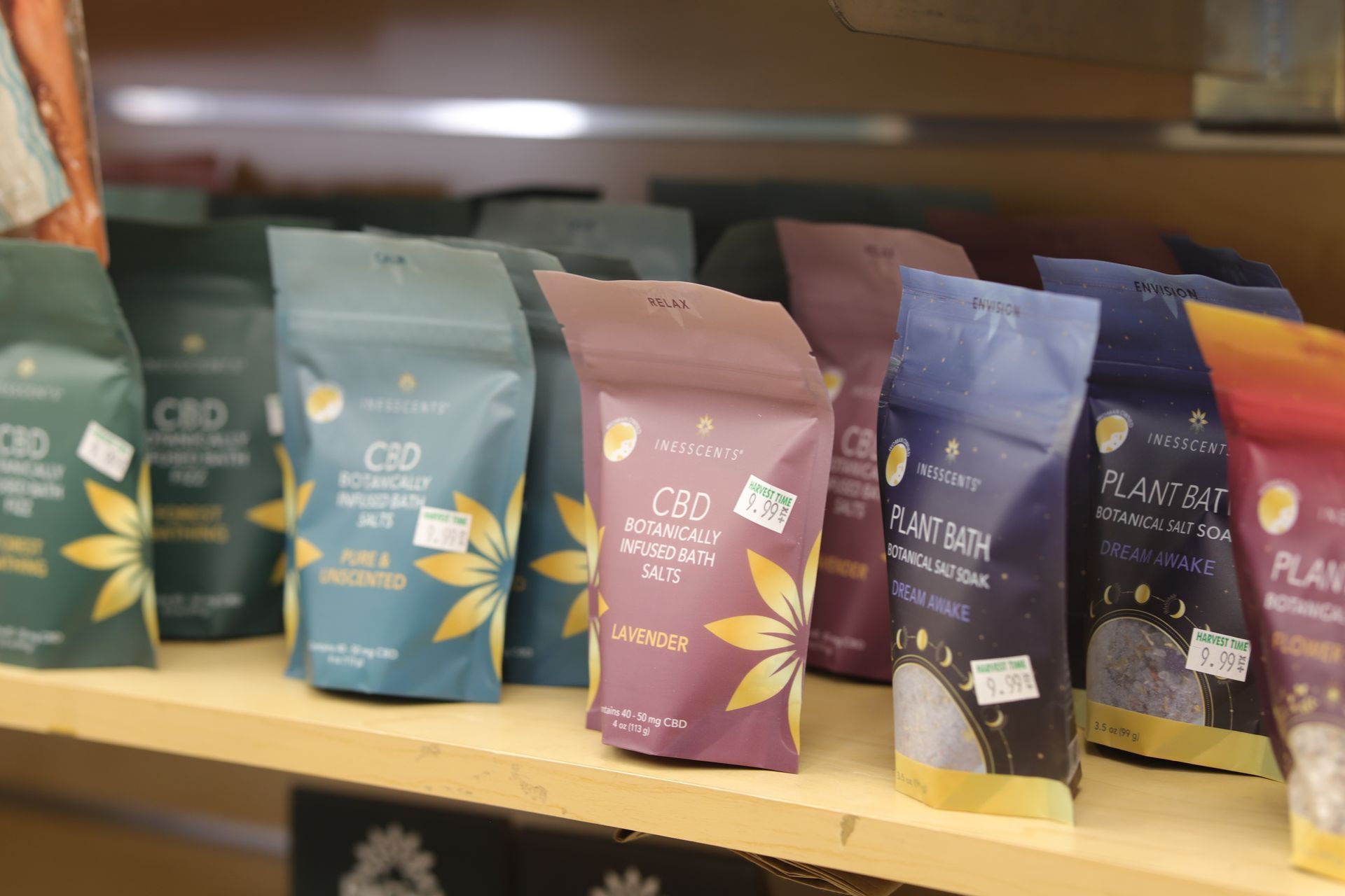 A row of colorful, branded pouches containing CBD or botanical bath products displayed on a retail store shelf.