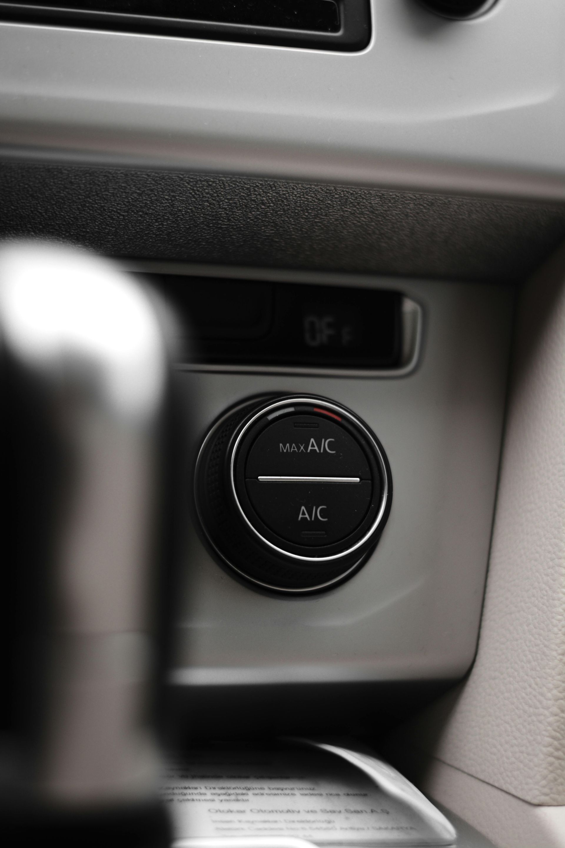 Car dashboard climate control knob with buttons, in a gray interior.