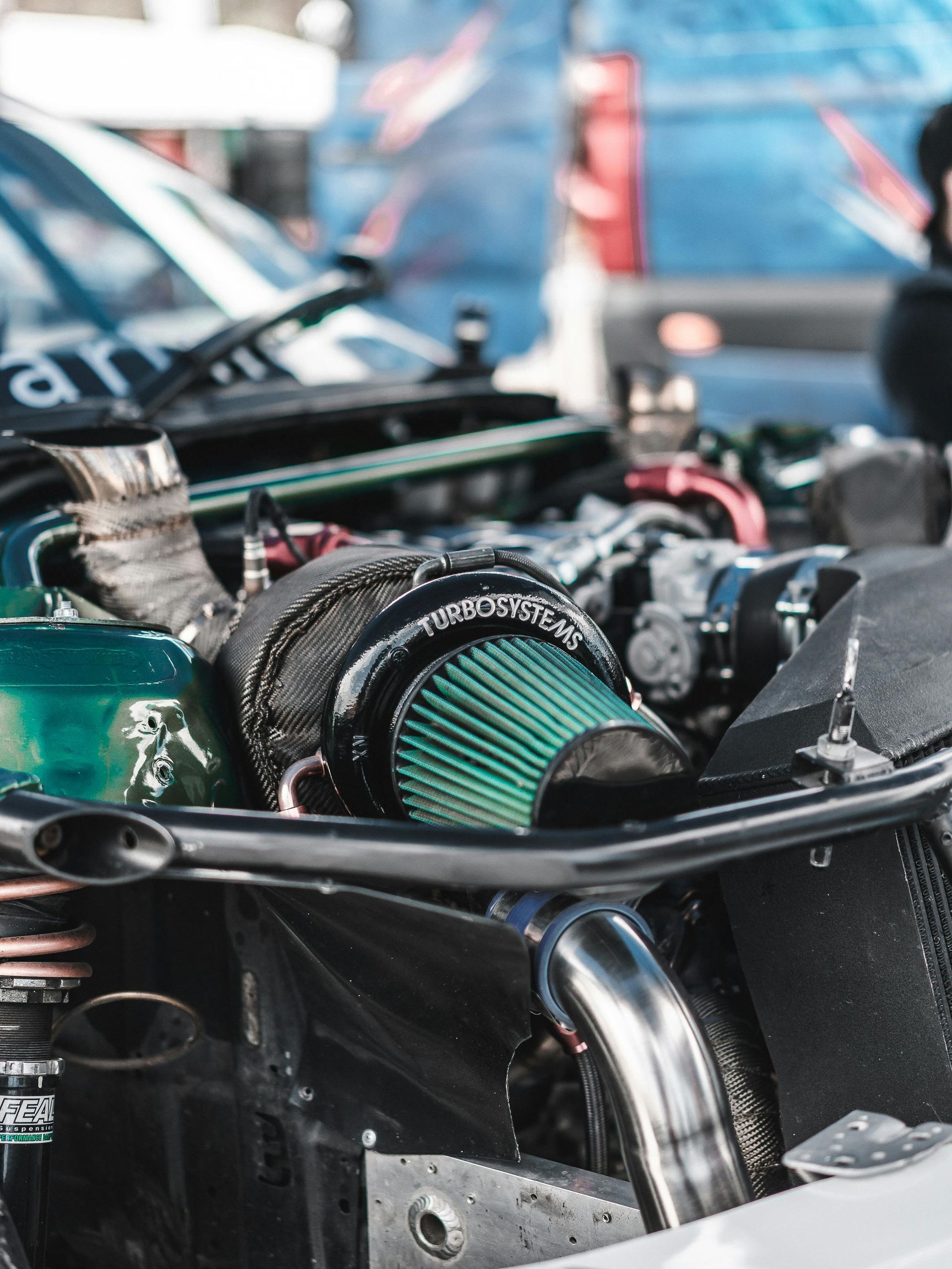 Close-up of a damaged race car engine with a green air filter and exposed parts