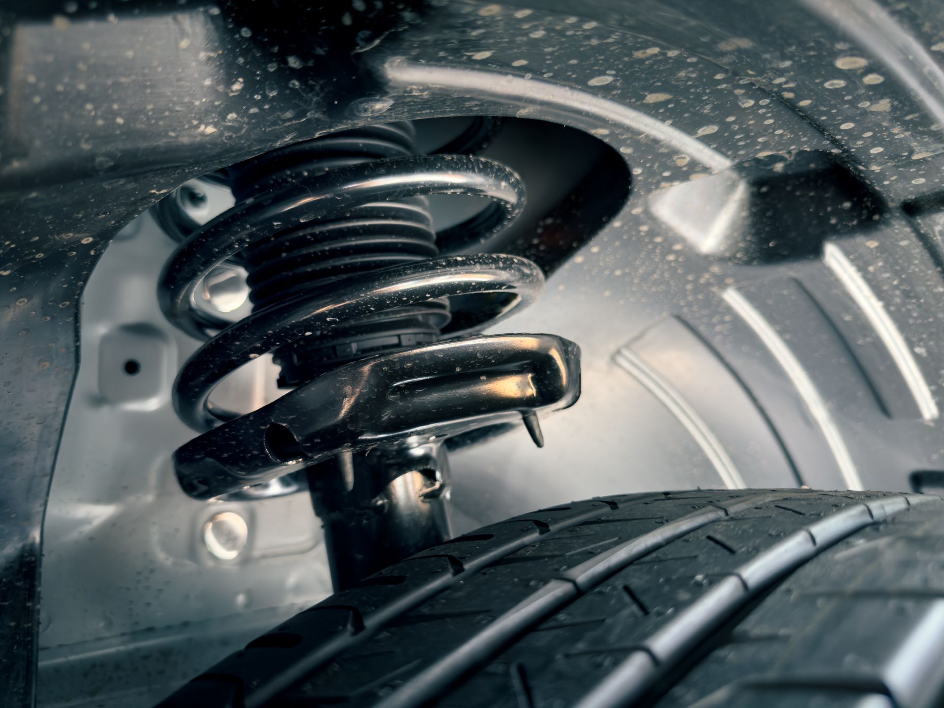 Close-up of a car wheel suspension and tire in a metallic wheel well