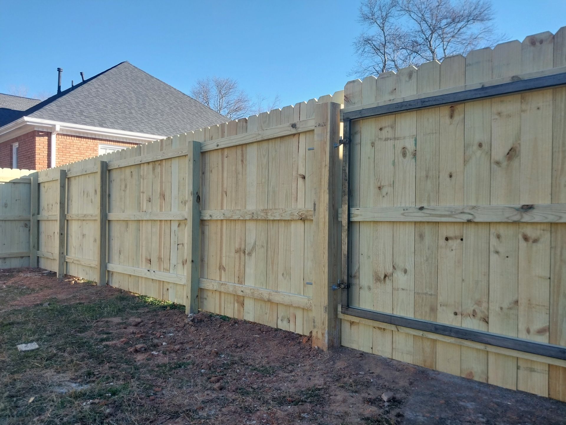 Wooden privacy fence along a residential yard under a clear blue sky