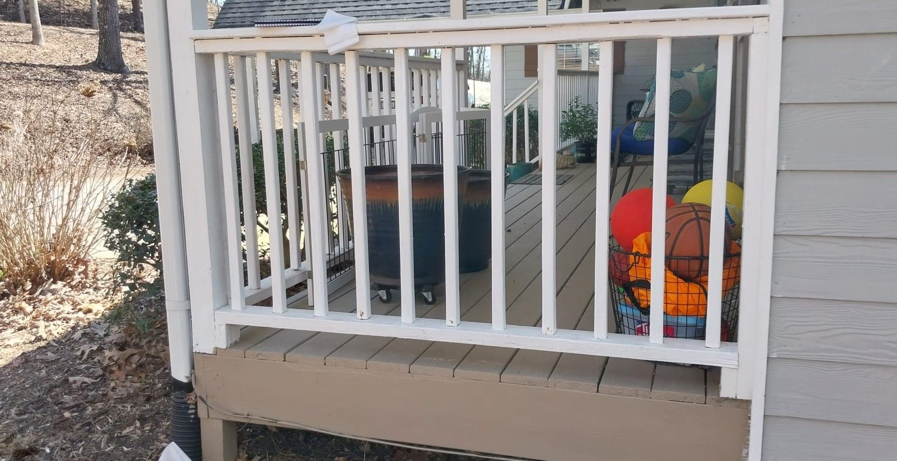 Small porch with white railing and outdoor toys, including an orange pumpkin decoration.