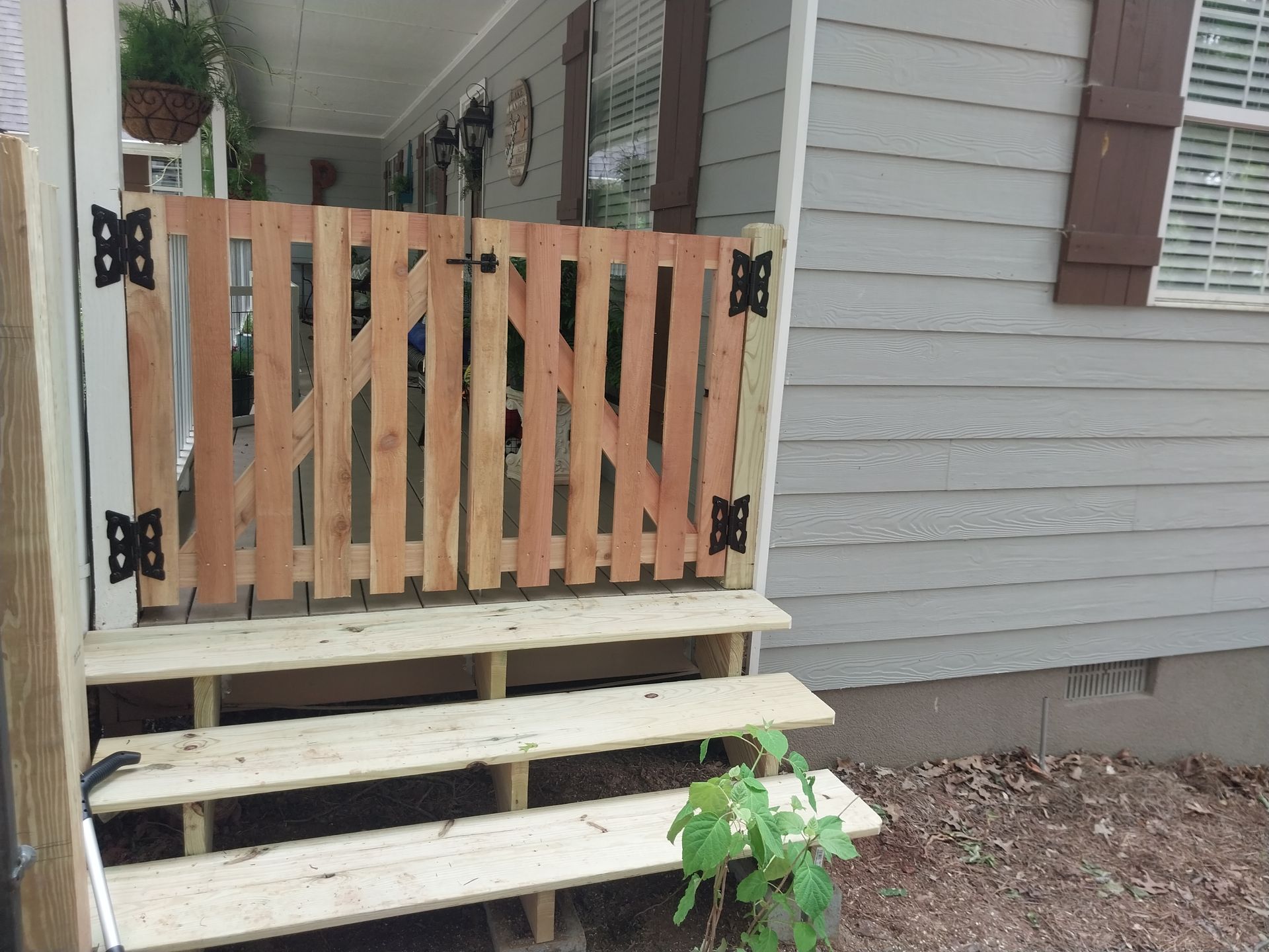 Wooden gate at top of backyard steps beside a house with light gray siding