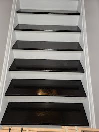 Black painted stairs with white risers. Wooden steps lead upward in a staircase.