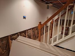 Basement renovation: staircase with exposed framing, drywall stack, and insulation.