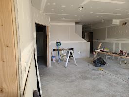 Interior under construction; drywall installation in progress. Room with unfinished walls, fireplace, and tools.