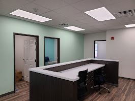 Reception area with a dark wood reception desk, light wood floors, and mint green and white walls.