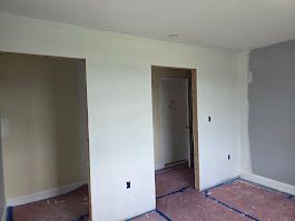 Interior room with white walls, two doorways, and unfinished flooring.