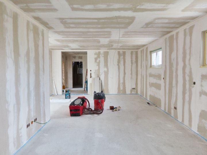 Interior view of a room under construction with exposed drywall and construction tools.
