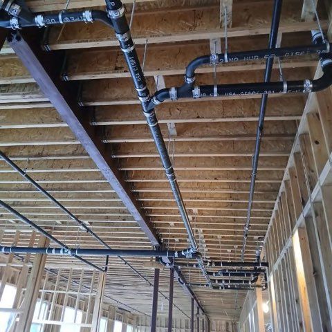 Professional plumbing services fixing sink pipes with wrench under kitchen cabinet repair work.