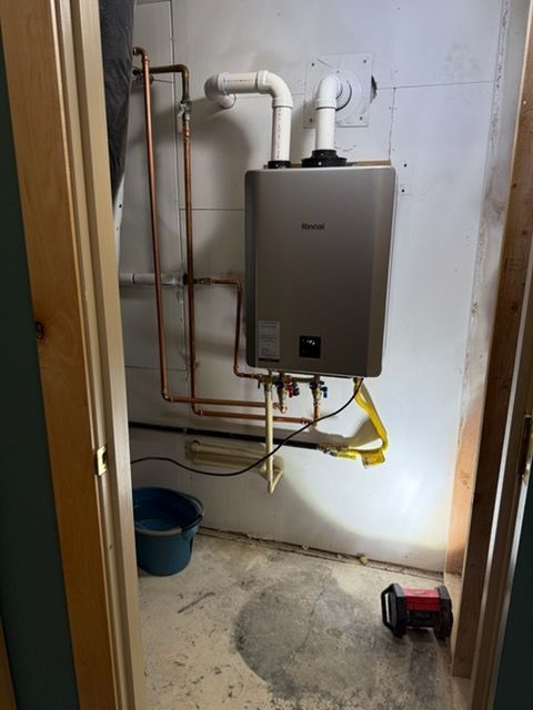 Utility room with a wall-mounted boiler, exposed copper pipes, and a blue bucket on the floor.
