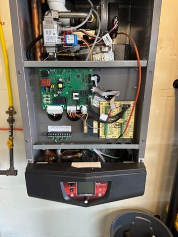 Open furnace with exposed wiring and circuit boards in a basement utility area