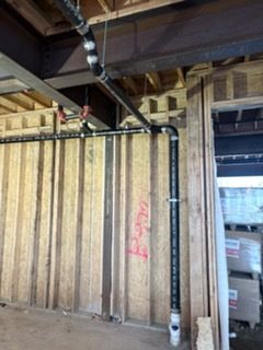 Interior of a construction area with exposed wood framing, beams, and a hanging striped barrier curtain.