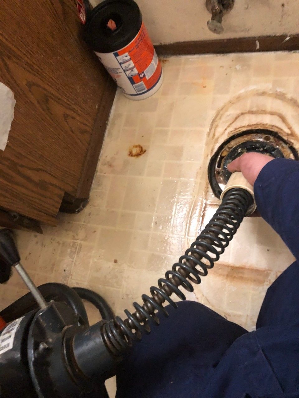 Service worker cleaning a drain with hydro jetting.