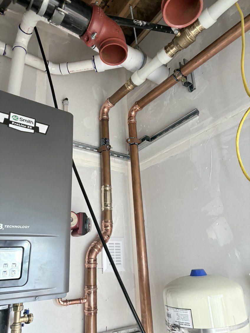 Basement utility area with furnace, copper pipes, red ducts, and a water heater.