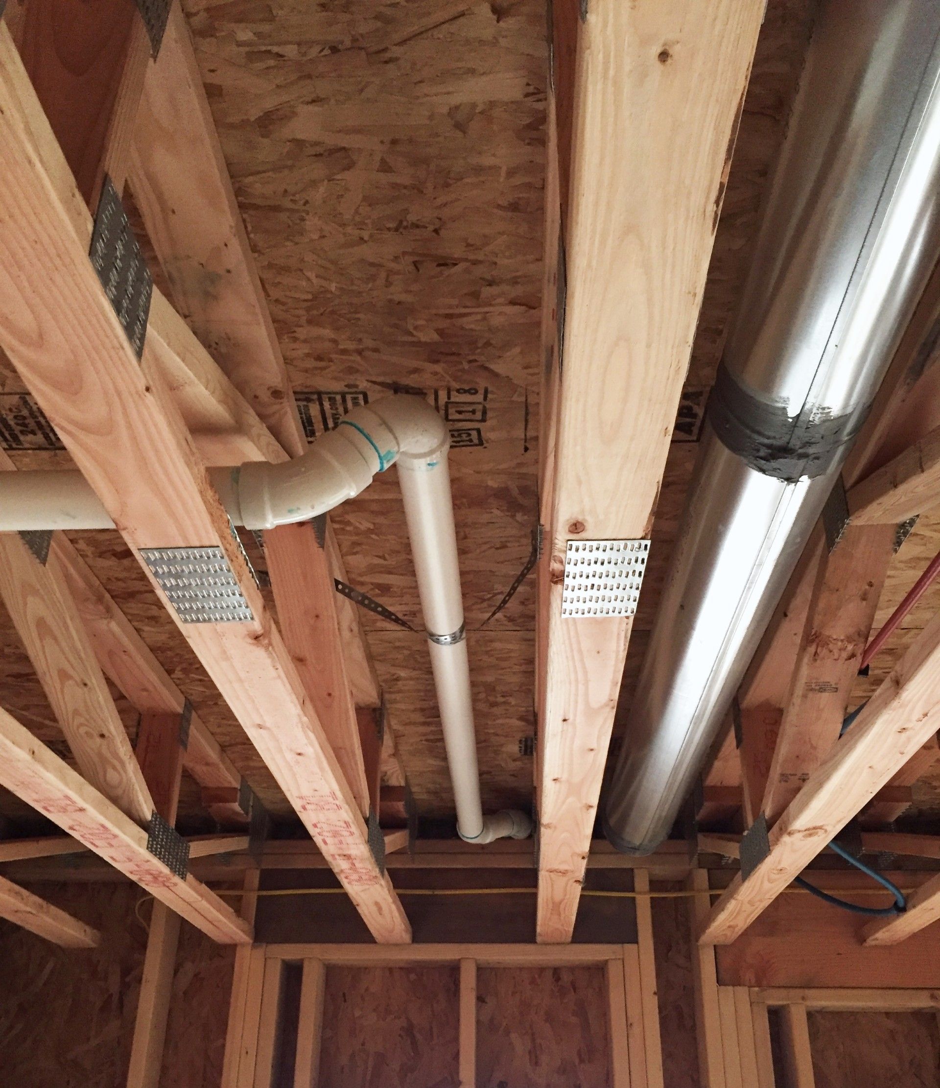 Wooden rafters and ceiling with PVC pipe and metal ductwork.